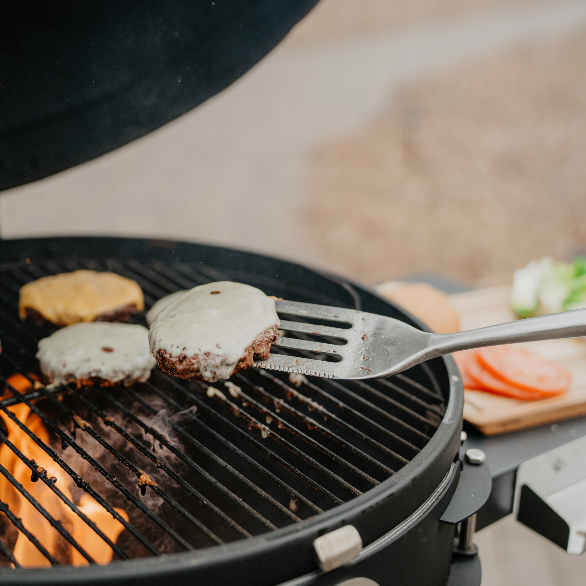 Hamburgers being cooked on a grill with a fork lifting one off the grill.