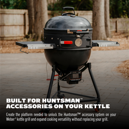 Black kettle grill with text about Huntsman accessories on a paved surface.