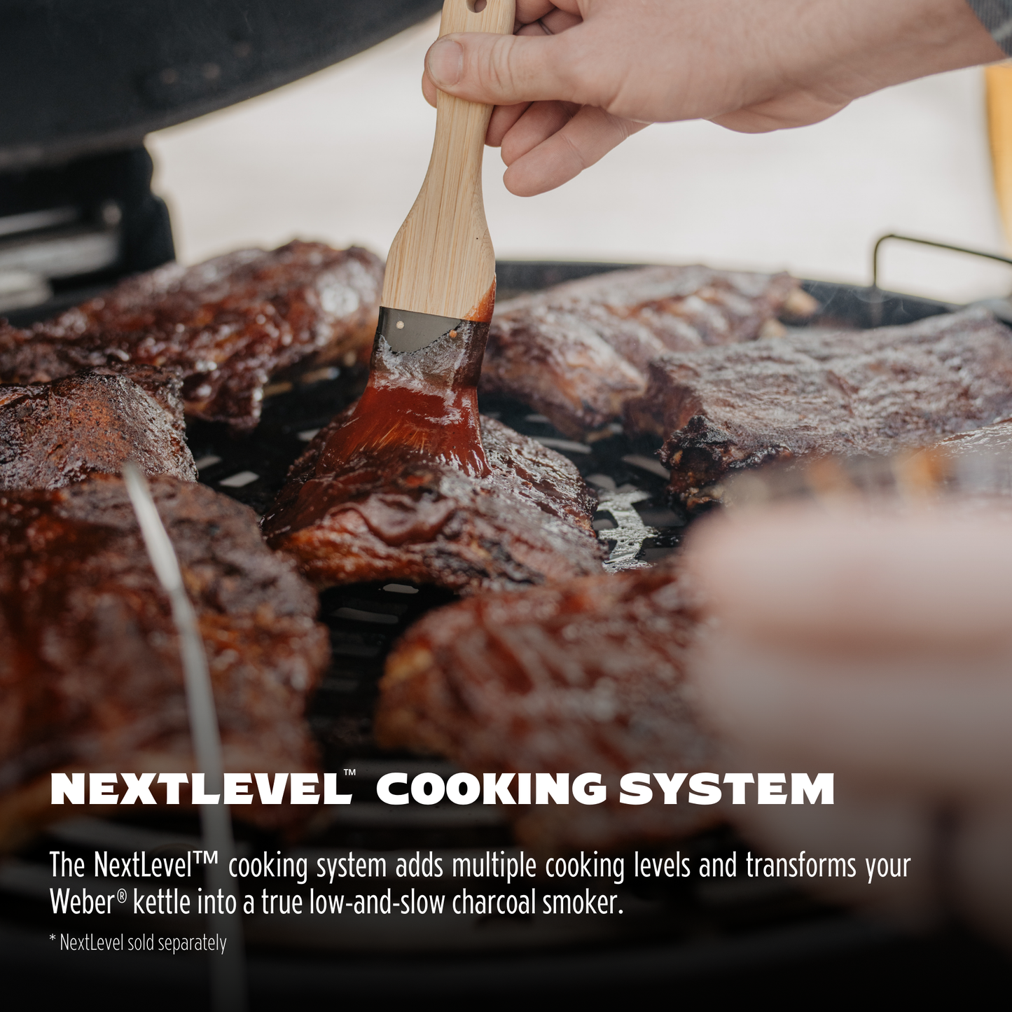 Person grilling meat with a brush, using the NextLevel cooking system on a grill.