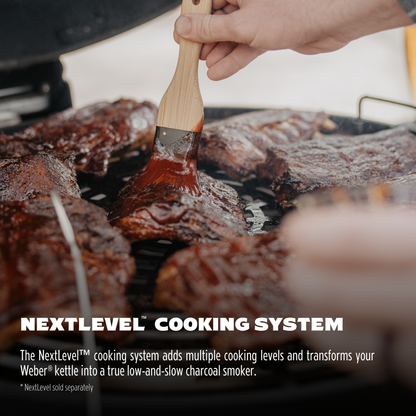 Person grilling meat with a brush, using the NextLevel cooking system on a grill.